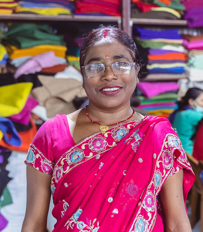 A picture of a stitching and sewing department artisan using a needle and thread to hand-stitch intricate details onto a garment, adding a personalized touch to the finished piece.